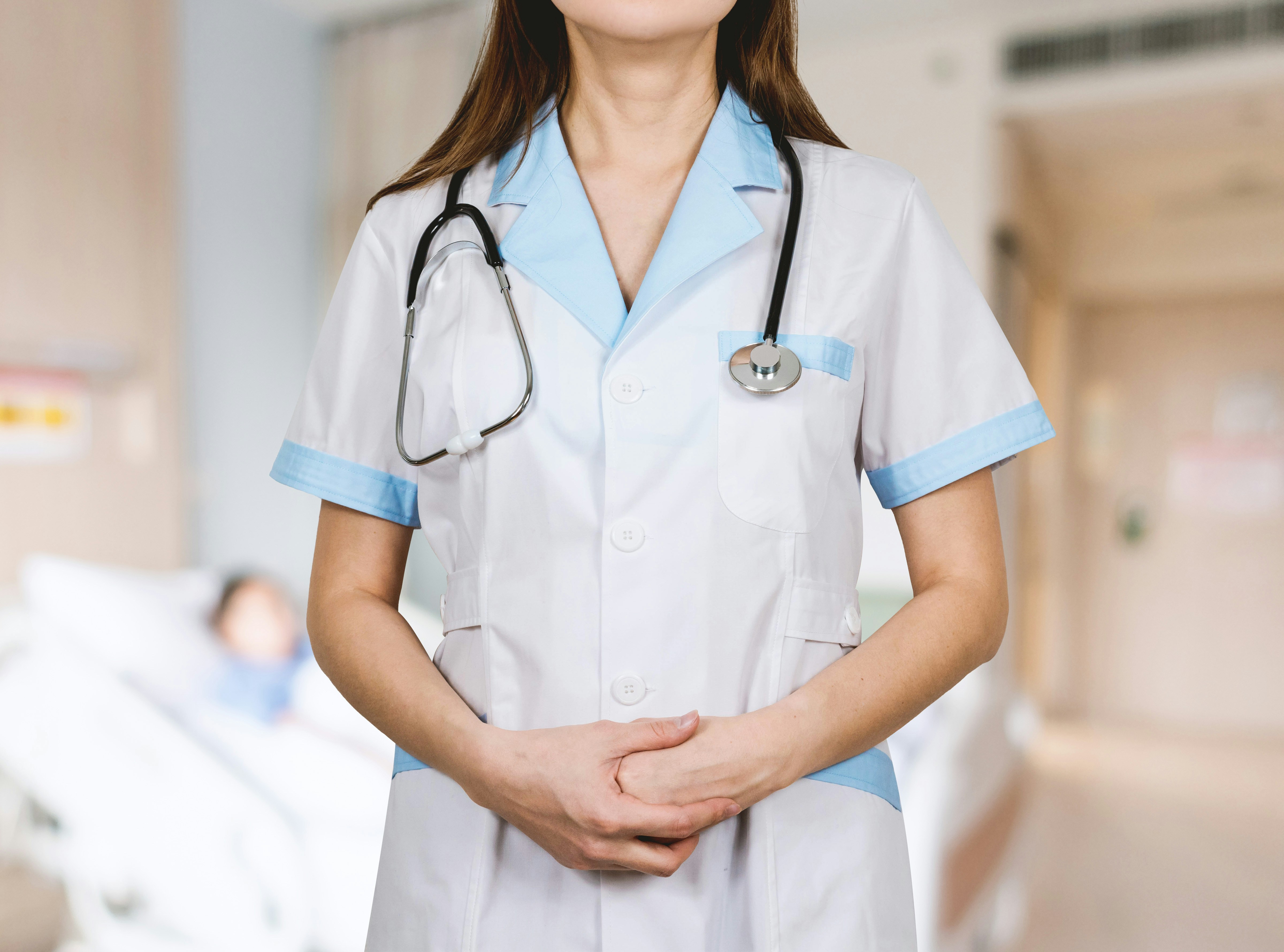 Healthcare clinician in a white coat with stethoscope, urgent care setting in background