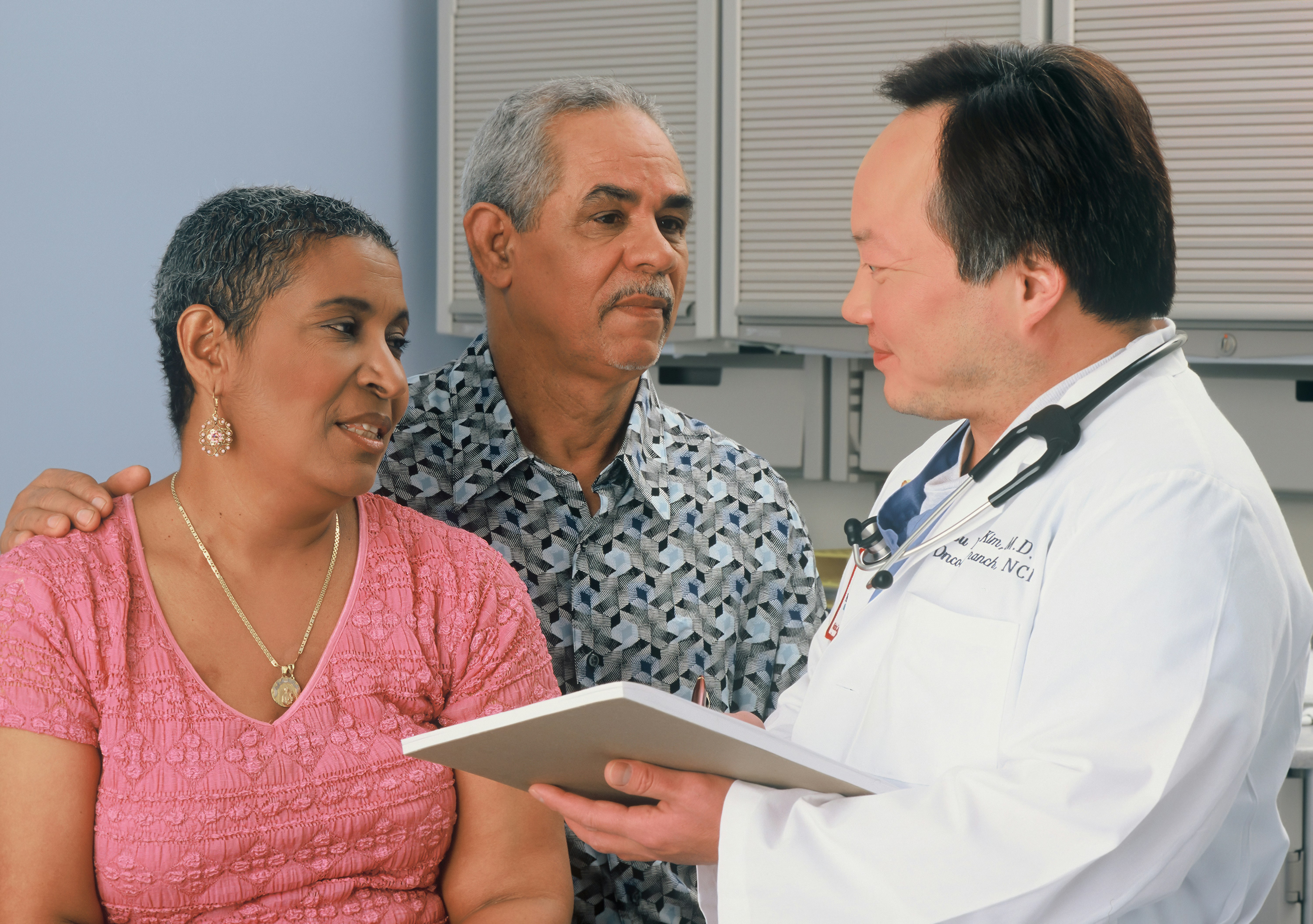 Physician with a patient and family member, attentive conversation in a clinic exam room